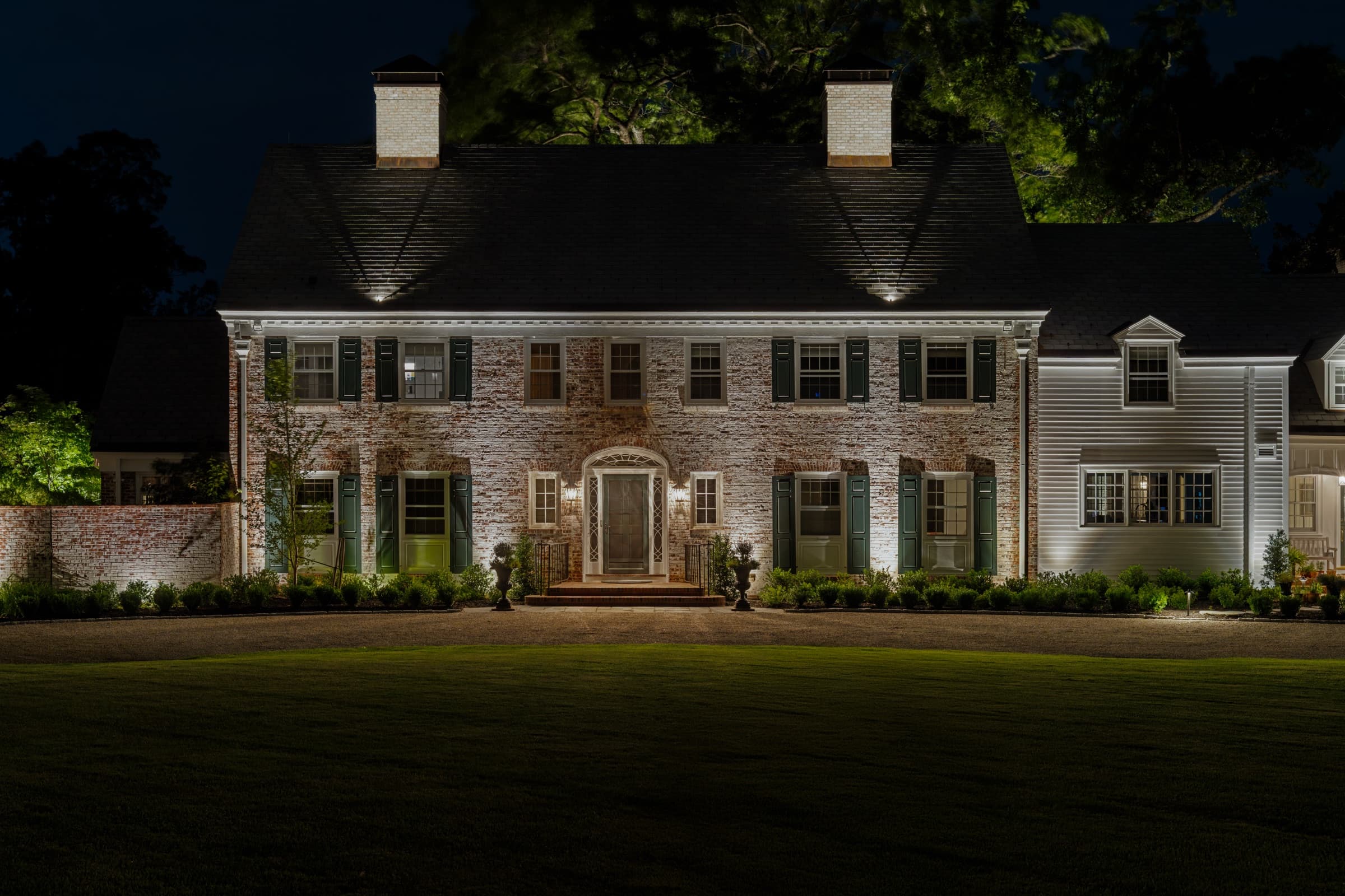 Brick façade grazed with warm light, lanterns either side of the front door