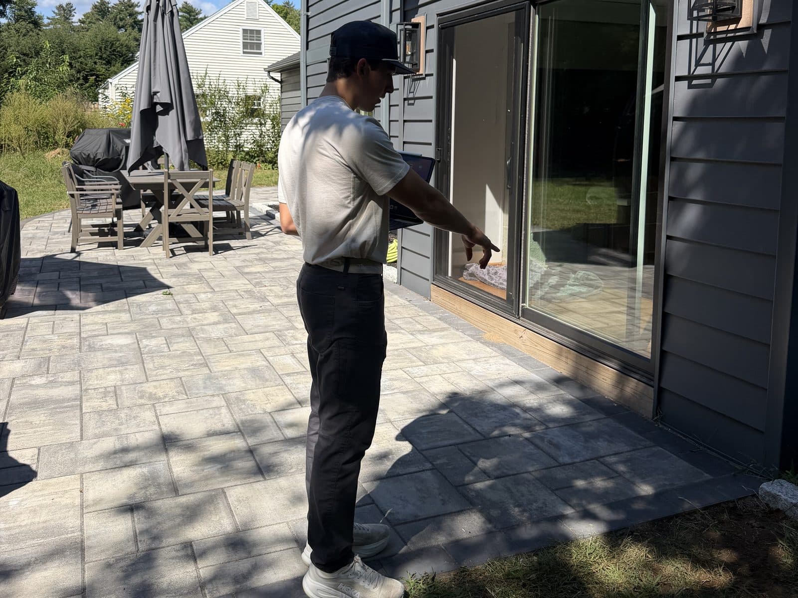 Walking a patio with a tablet, pointing out the view through a sliding door
